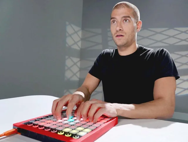 Xander Corvus in a black tee playing a music pad